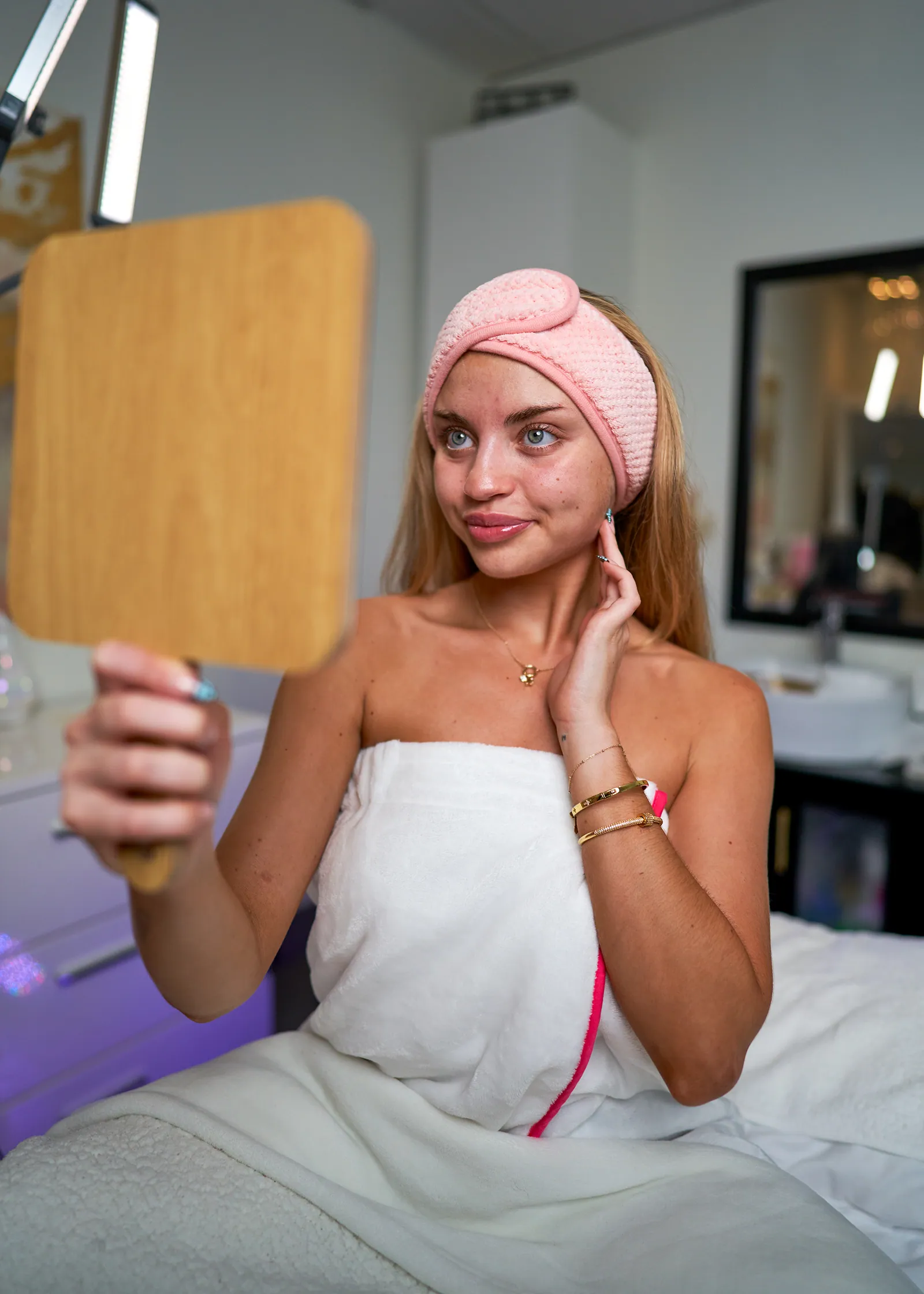 A client checking her skin in a hand mirror after a facial